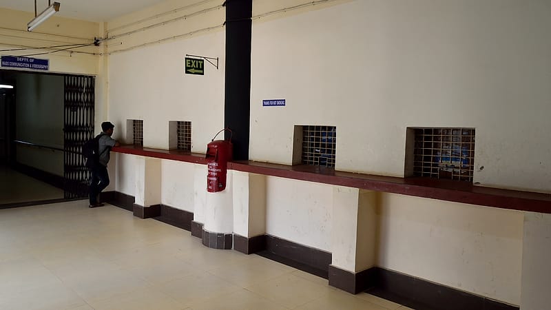A clerk's counter with a rubber date stamp, an ink pad, a wire tray of forms and a queue rail in the foreground.