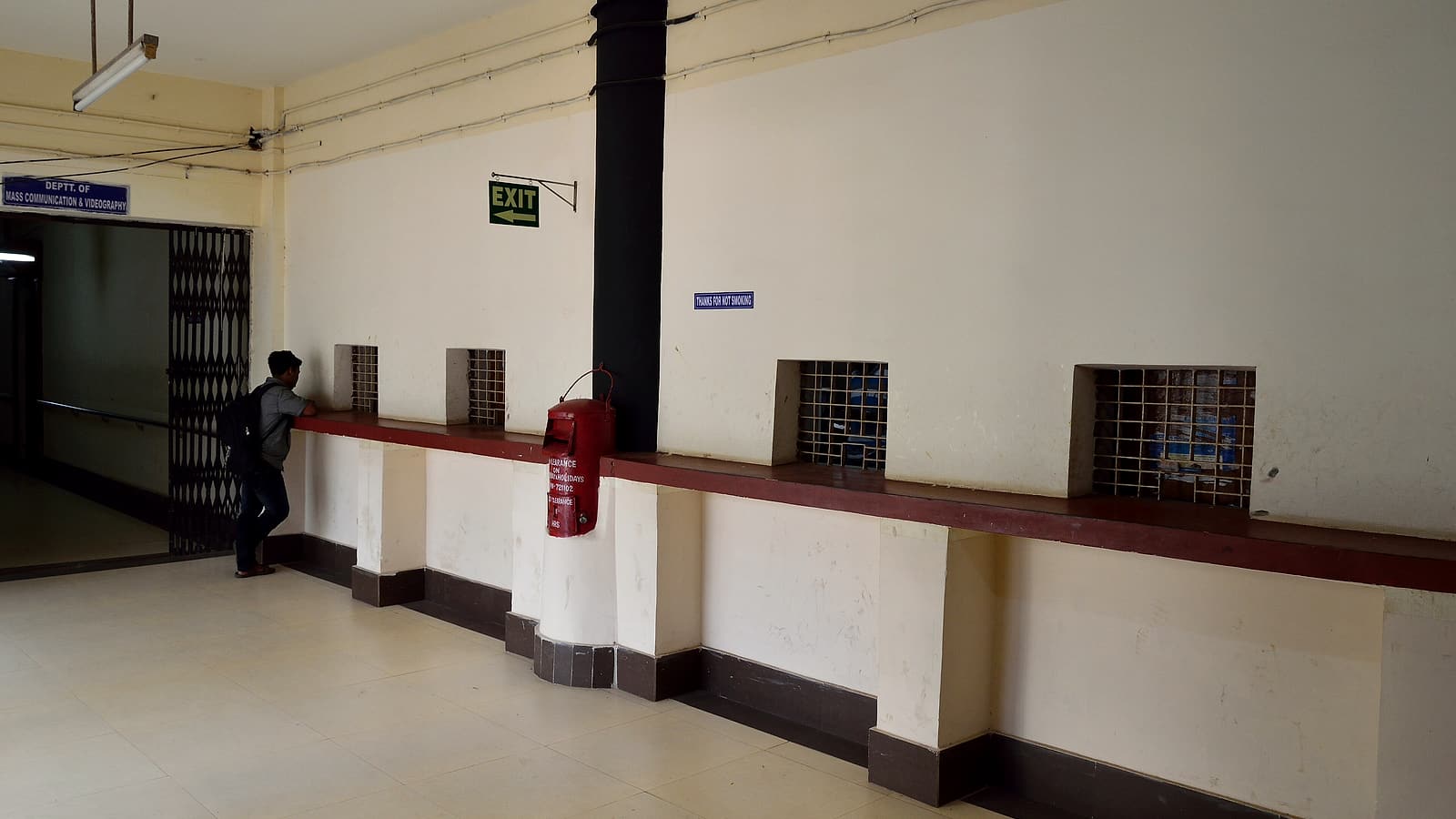 A clerk's counter with a rubber date stamp, an ink pad, a wire tray of forms and a queue rail in the foreground.
